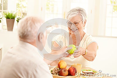 Laughing senior wife getting apple from husband Stock Photo