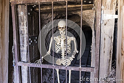 Laughing skeleton trapped inside a closed mine shaft Stock Photo