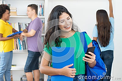 Laughing spanish female student with backpack and mobile phone Stock Photo