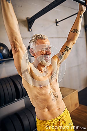 High-spirited athlete performing a dead hang exercise Stock Photo