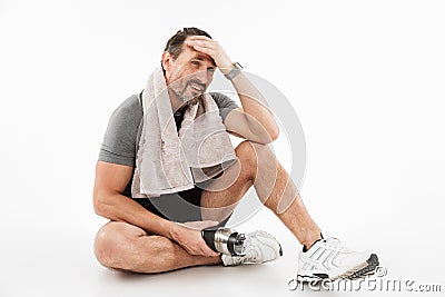 Laughing strong mature sportsman sitting with towel and water Stock Photo