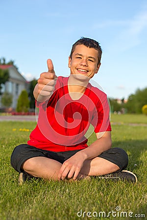 Laughing teenage summer in the grass thumbs up Stock Photo