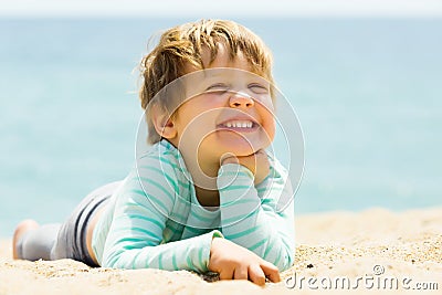 Laughing three-year girl laying on beach Stock Photo