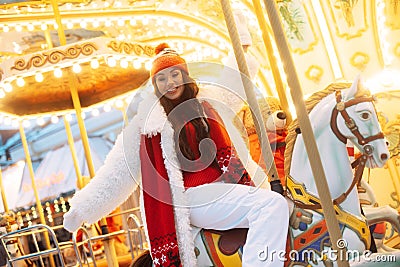 Laughing young woman at the winter fair riding a horse, carousel, Christmas carelessness and fun. Stock Photo