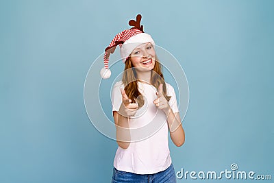 Laughing young santa girl in funny decorative deer horns on her head, pointing Stock Photo