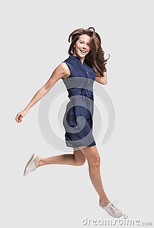 Laughing young woman jumping, having fun and enjoying life, beautiful joyful girl full length isolated studio portrait Stock Photo