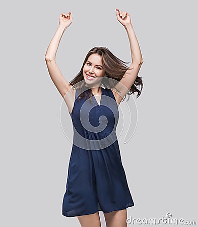 Laughing young woman with raised arms having fun and enjoying life. Beautiful joyful girl is celebrating or dancing. Stock Photo