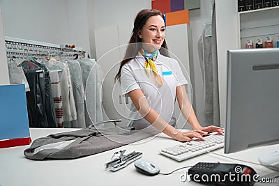 Laundry administrator checking information about clients garment on computer Stock Photo