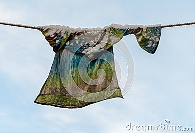 Laundry with snow, colourful sweater left behind outside, drying on the clothesline in the winter. Blue sky and white Stock Photo