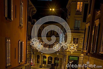 Lausanne, Vaud, Switzerland - 01.10.2021: Night illuminated scenery of street and road with decorated Christmas light with Manor Editorial Stock Photo