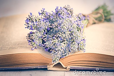Lavender bouquet laid over an old book on a white wooden background. Vintage style. Stock Photo