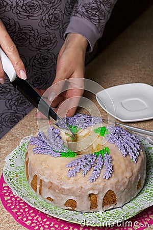 Lavender Cupcake. Sugar coated. Decorated with lavender glaze flowers. A woman cuts a small piece from him Stock Photo