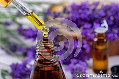 Lavender essential oil drop from pipette over the bottle Stock Photo