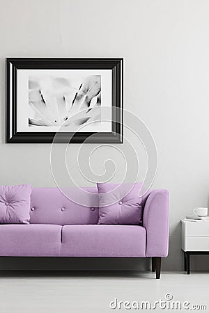 Lavender purple, trendy sofa and a framed photo mock-up in a gray living room interior with place for a lamp Stock Photo