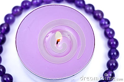 Lavender tea light candle surrounded by royal purple amethyst bead bracelet Stock Photo