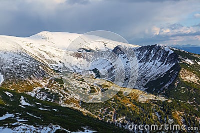 Lawn covered with white snow. Majestic spring sunny day. Beautiful landscape of high mountains and forests. Wallpaper background. Stock Photo