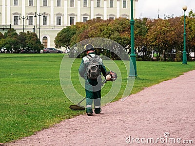 Lawn mower from the back at work. City service, maintenance of the city lawn in the Park. Editorial Stock Photo