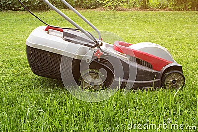 Lawn mower on a green meadow. Lawn Mower In Garden. Details of landscaping and gardening Stock Photo