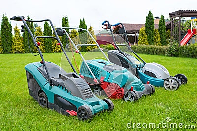 . Lawn mowers are standing on the lawn in the garden backyard. A close-up of an electric lawn mower Stock Photo