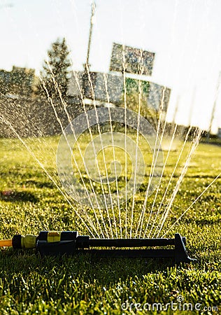 Lawn sprinkler spraying water over green grass. Modern device of irrigation garden grass. Irrigation system - technique Stock Photo