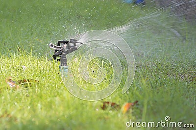 Lawn water sprinkler spraying water over grass Stock Photo