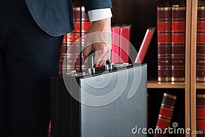 Lawyer Carrying Briefcase Against Bookshelf Stock Photo