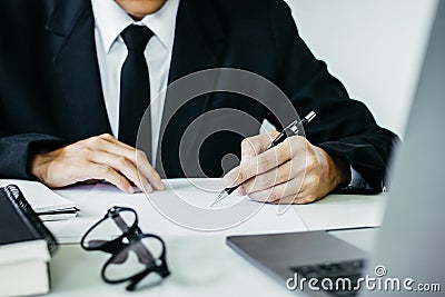 The lawyer, handwriting civil and criminal indictment on the desk with laptop and glasses working at the home office Stock Photo