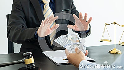 The lawyer was offered money, but he refused the client`s offer on a table with a hammer and golden scales Stock Photo