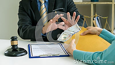 The lawyer was offered money, but he refused the client`s offer on a table with a hammer and golden scales. Stock Photo