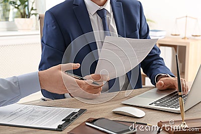 Lawyer working with client at table in office, focus Stock Photo