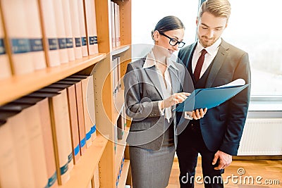 Lawyers in library of law firm discussing strategy in a case holding file Stock Photo