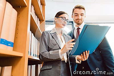 Lawyers in library of law firm discussing strategy in a case holding file Stock Photo