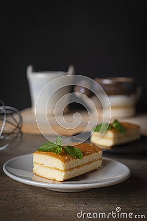 Layer vanilla flavoured cake place on white plate on the wooden table there are black plate and Stock Photo