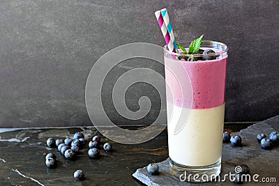 Layered blueberry and coconut smoothie against a dark slate background Stock Photo