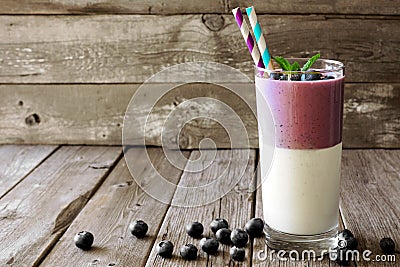 Layered blueberry and coconut smoothie against a rustic wood background Stock Photo