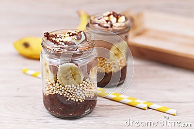 Layered healthy dessert with banana fruit slices, puffed quinoa grain and chocolate chia seed pudding in jar Stock Photo