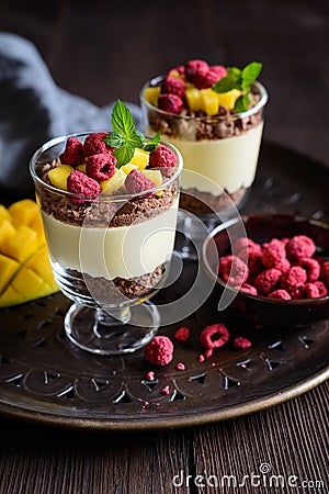 Layered mango dessert with cream cheese, crushed biscuits and freeze dried raspberries Stock Photo