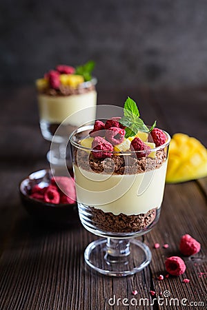 Layered mango dessert with cream cheese, crushed biscuits and freeze dried raspberries Stock Photo