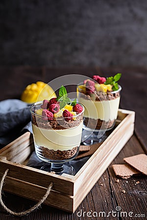 Layered mango dessert with cream cheese, crushed biscuits and freeze dried raspberriesLayered mango dessert with cream cheese, cru Stock Photo