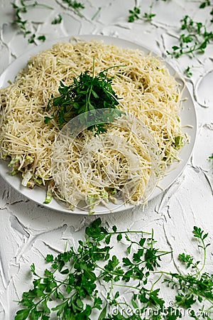 Layered salad with grated hard cheese with lettuce leaves and watercress greens on a white concrete background Stock Photo