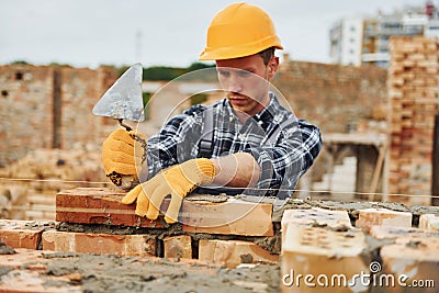 Laying bricks. Construction worker in uniform and safety equipment have job on building Stock Photo