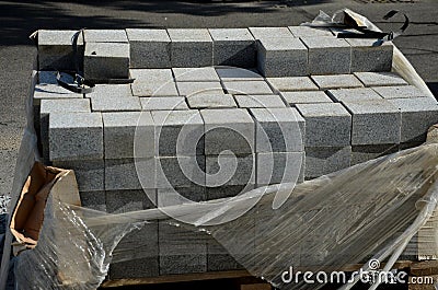 Laying granite and marble light, white gray, medium size cubes. tilers put cobblestones in sand or gravel. they have piles ready Stock Photo