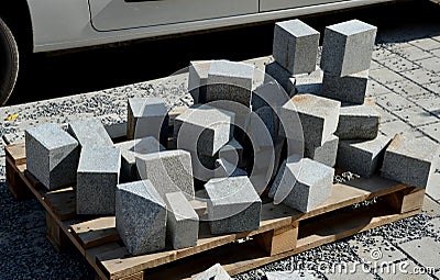 Laying granite and marble light, white gray, medium size cubes. tilers put cobblestones in sand or gravel. they have piles ready Stock Photo