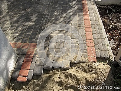 Laying gray and red sidewalk tiles in the yard Stock Photo