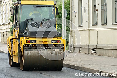 Laying of new modern asphalt. Asphalt laying equipment works on the site. A yellow asphalt skating rink rides in close-up on a new Editorial Stock Photo