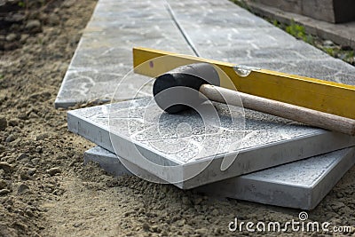 Laying a paving stone or brick. Gray concrete slabs in house courtyard on sand foundation base Stock Photo