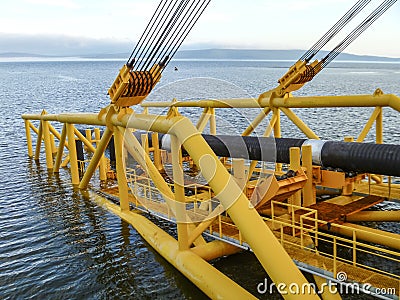 Laying of pipes with pipe-laying barge crane near the shore. Descent of the pipeline to a bottom exhausting with the pipelaying b Stock Photo