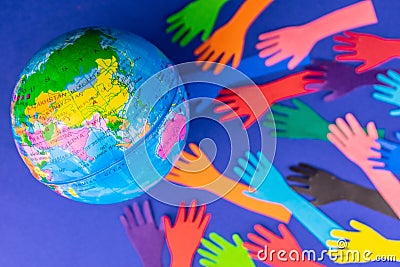 Layout of the earth and many colored hands on a blue background. The concept of saving the planet earth. Stock Photo