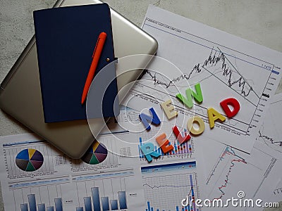 Layout of a laptop, Notepad, pen, and letters on the background of graphs and charts Stock Photo