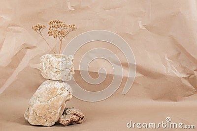 Layout made of from a pile of balancing stones and dry flower on craft beige background. Front view Copy space Monochrom Stock Photo